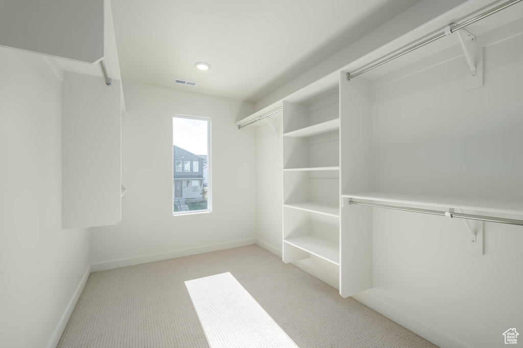 Walk in closet featuring light colored carpet
