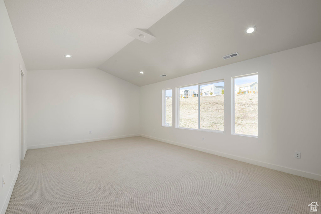 Spare room featuring light colored carpet and lofted ceiling