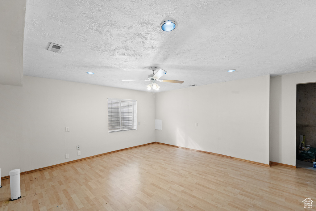 Unfurnished room featuring a textured ceiling, light hardwood / wood-style flooring, and ceiling fan