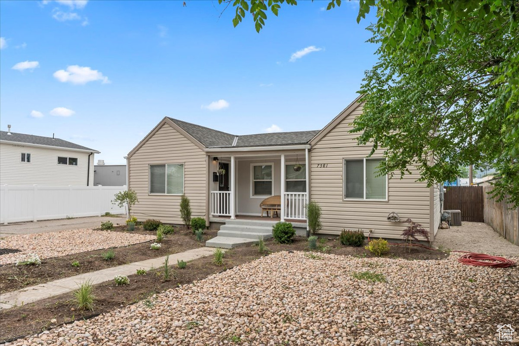 Ranch-style home with covered porch, cooling unit, a fenced backyard, and roof with shingles