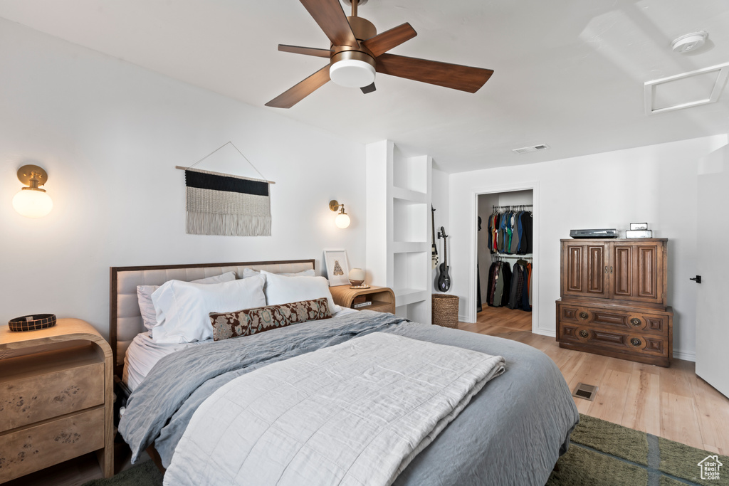Bedroom with light hardwood / wood-style floors, a closet, ceiling fan, and a spacious closet