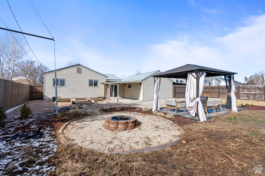 Rear view of property featuring a patio area, a gazebo, and a fire pit