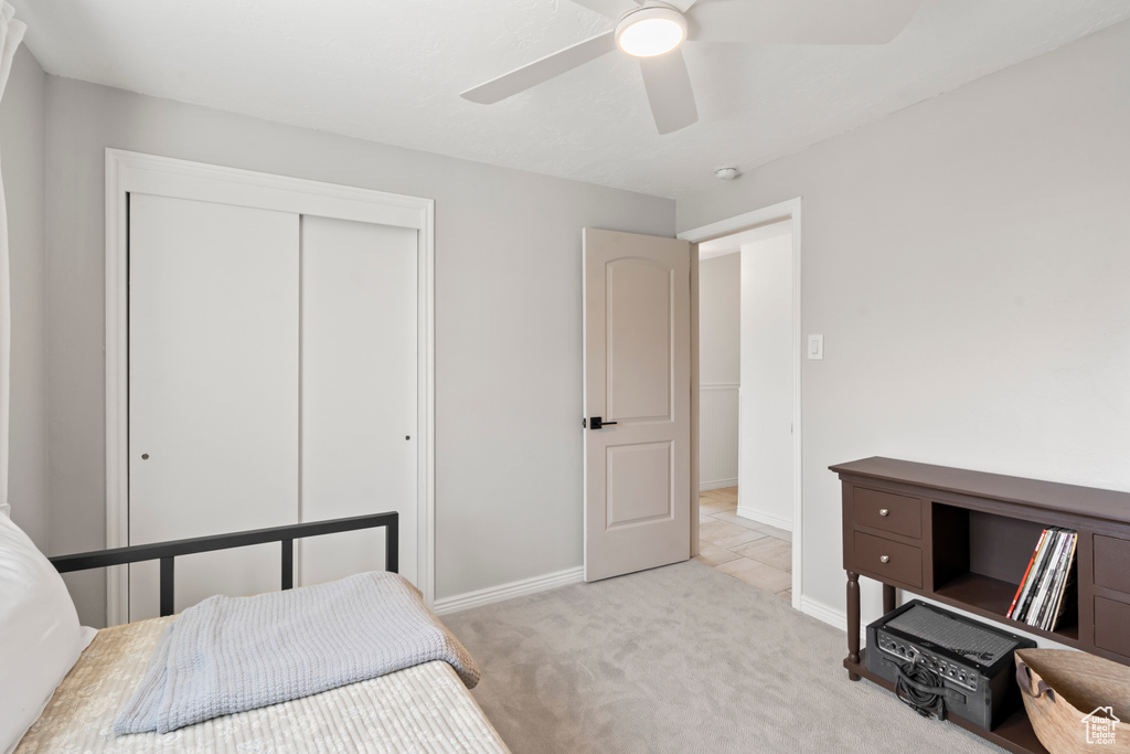 Bedroom with light carpet, a closet, and ceiling fan