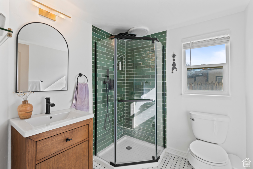 Bathroom featuring an enclosed shower, vanity, and toilet