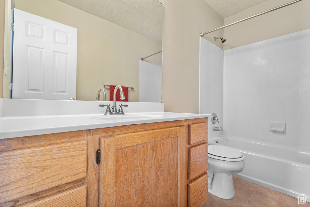 Full bathroom featuring toilet, shower / washtub combination, a textured ceiling, tile patterned floors, and vanity