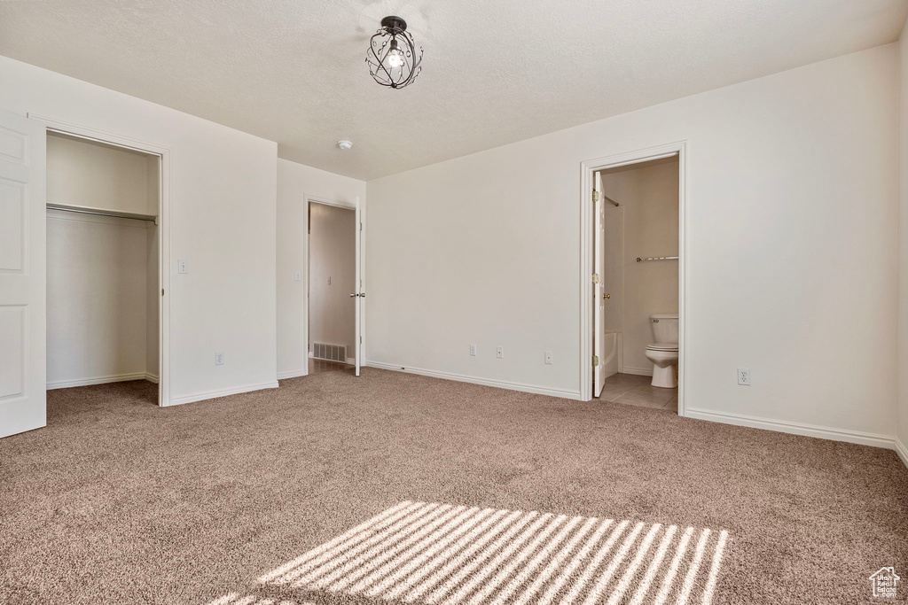 Unfurnished bedroom with carpet, a textured ceiling, and connected bathroom