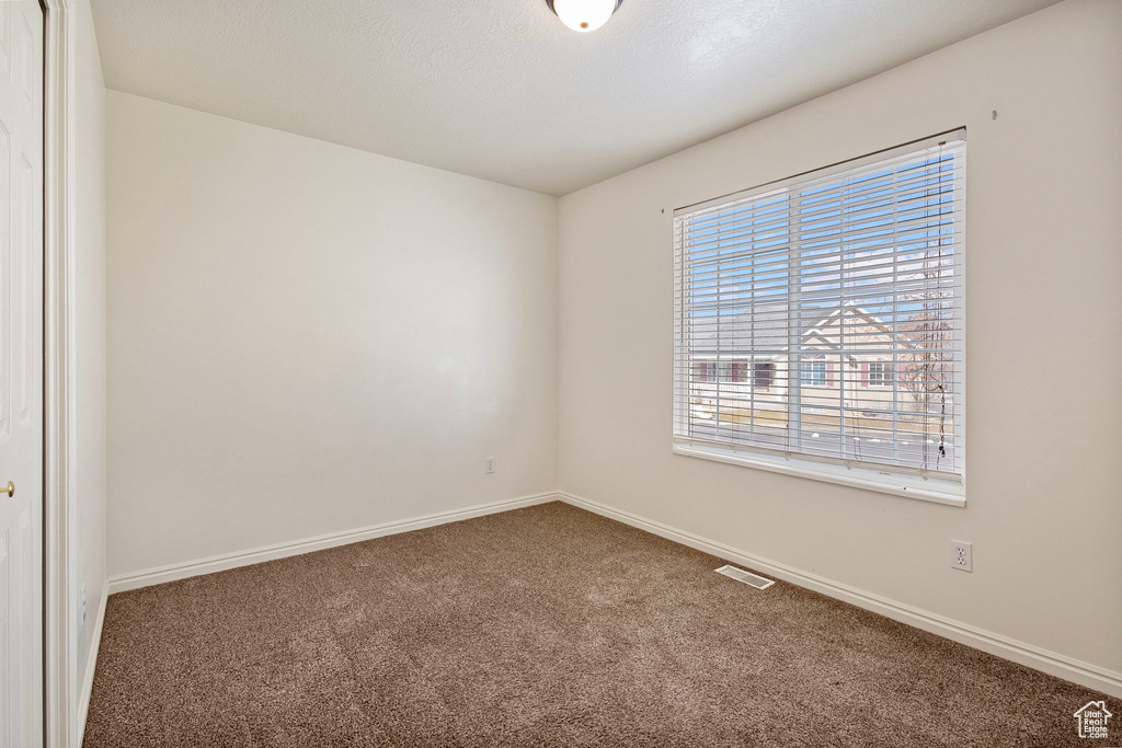 Carpeted spare room featuring a textured ceiling