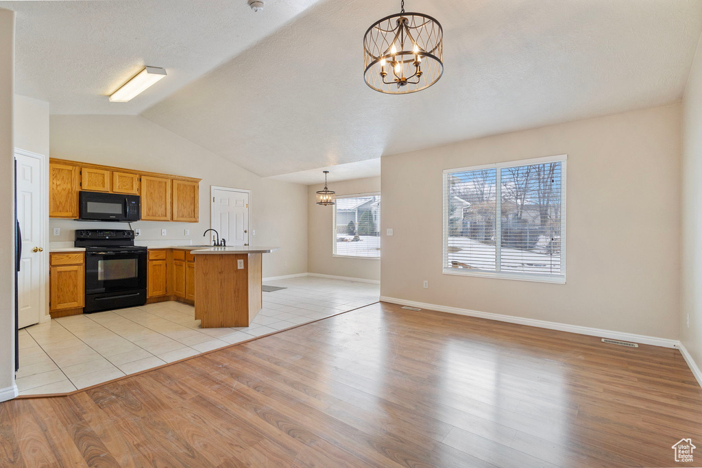 Kitchen featuring black appliances, an inviting chandelier, light hardwood / wood-style floors, sink, and pendant lighting