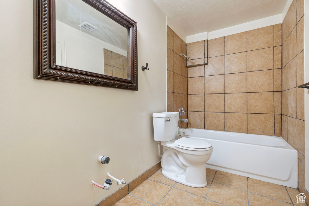 Bathroom with tiled shower / bath, toilet, and tile patterned floors