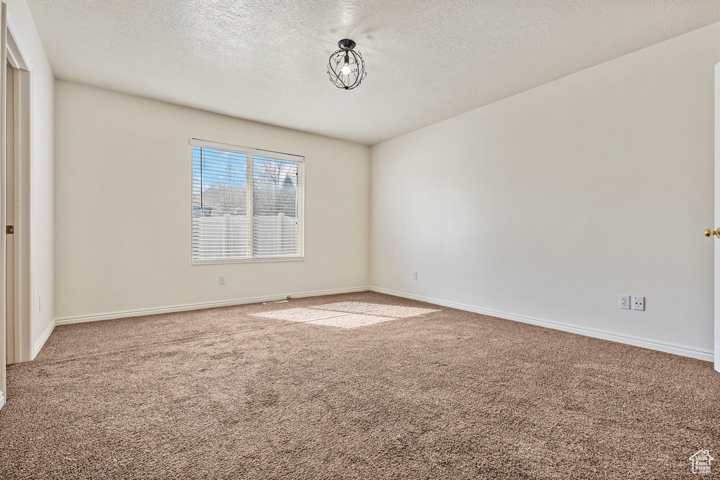 Empty room with carpet and a textured ceiling