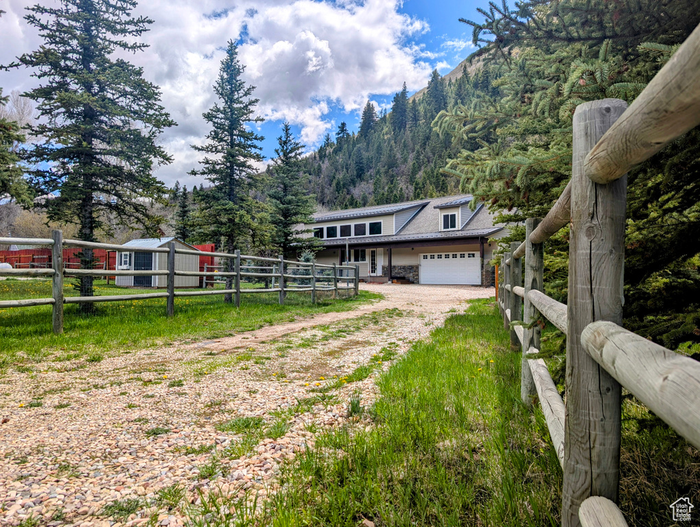 View of front facade featuring driveway, an attached garage, fence, a mountain view, and a view of trees