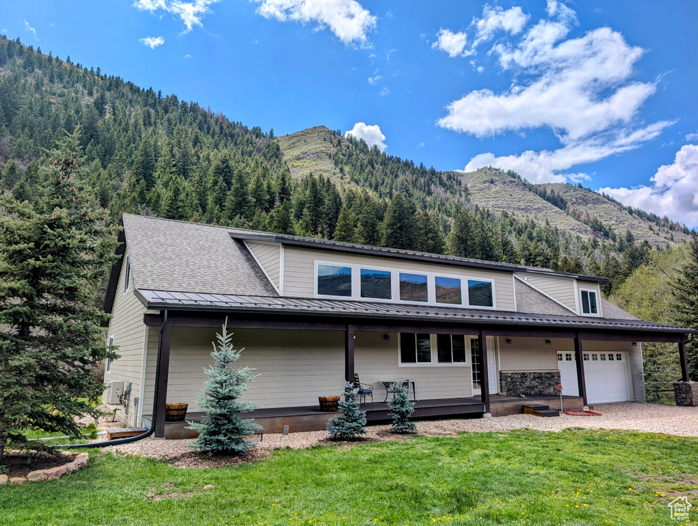 View of front of property featuring a mountain view, a front lawn, an attached garage, and driveway