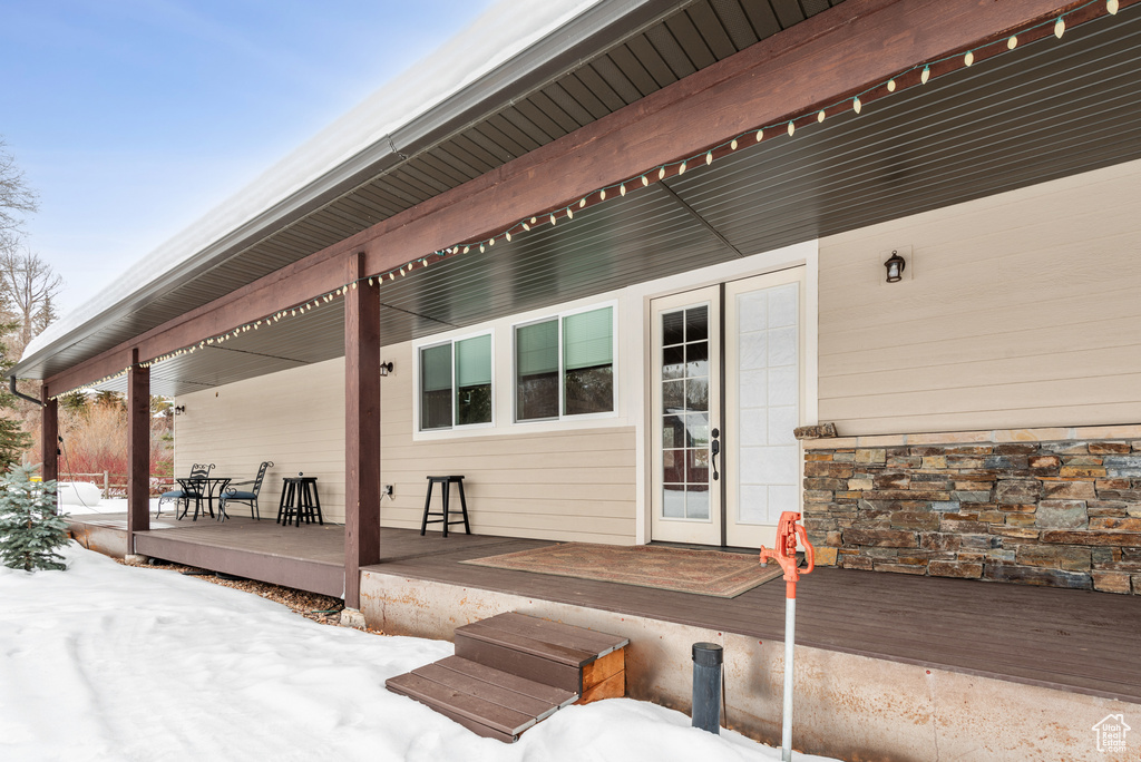 Snow covered property entrance featuring a wooden deck