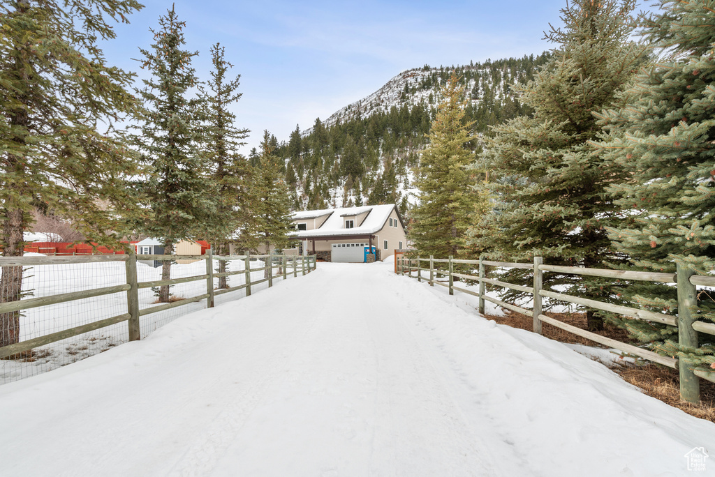 Yard layered in snow featuring a garage and a mountain view