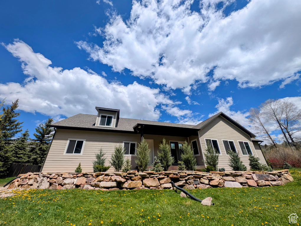View of front facade featuring a front yard and a shingled roof