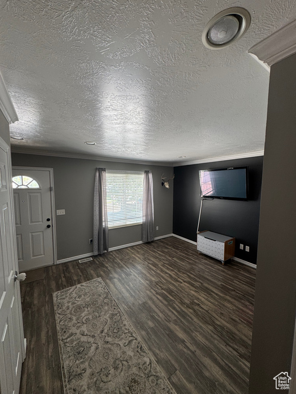 Foyer with a textured ceiling, wood finished floors, baseboards, and ornamental molding