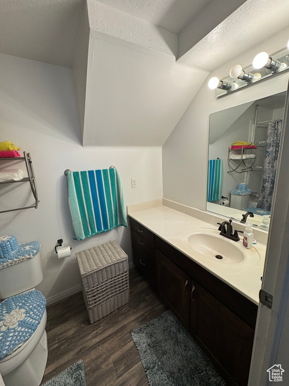 Full bath featuring wood finished floors, toilet, vanity, and vaulted ceiling