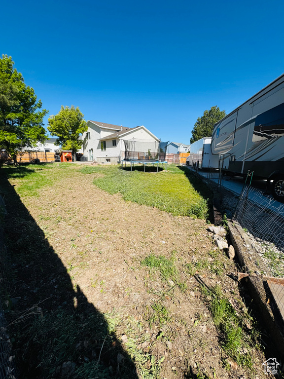 View of yard featuring a trampoline, fence, and a residential view