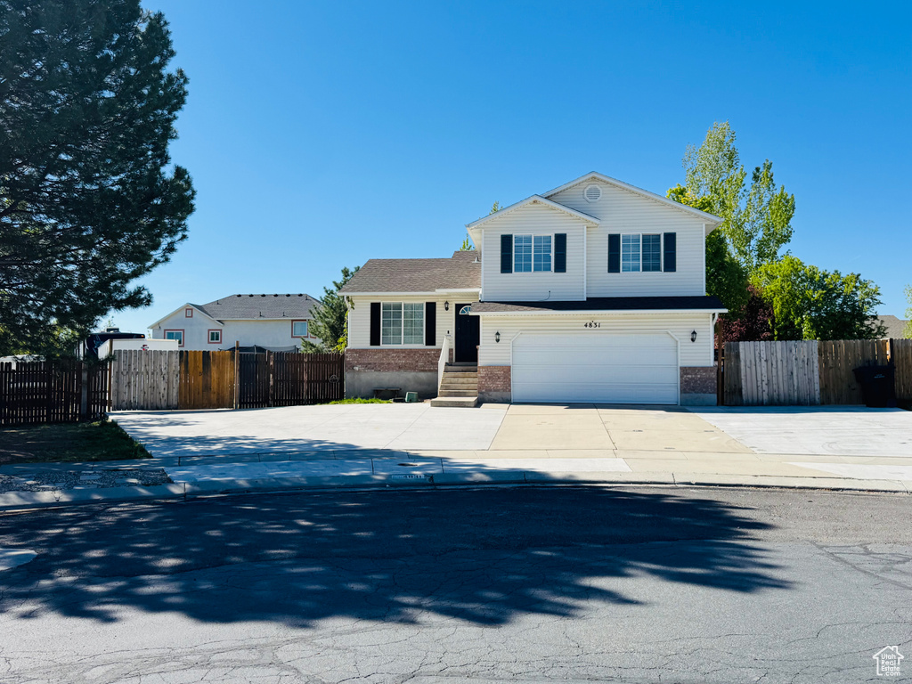 Traditional-style home with concrete driveway, brick siding, an attached garage, and fence