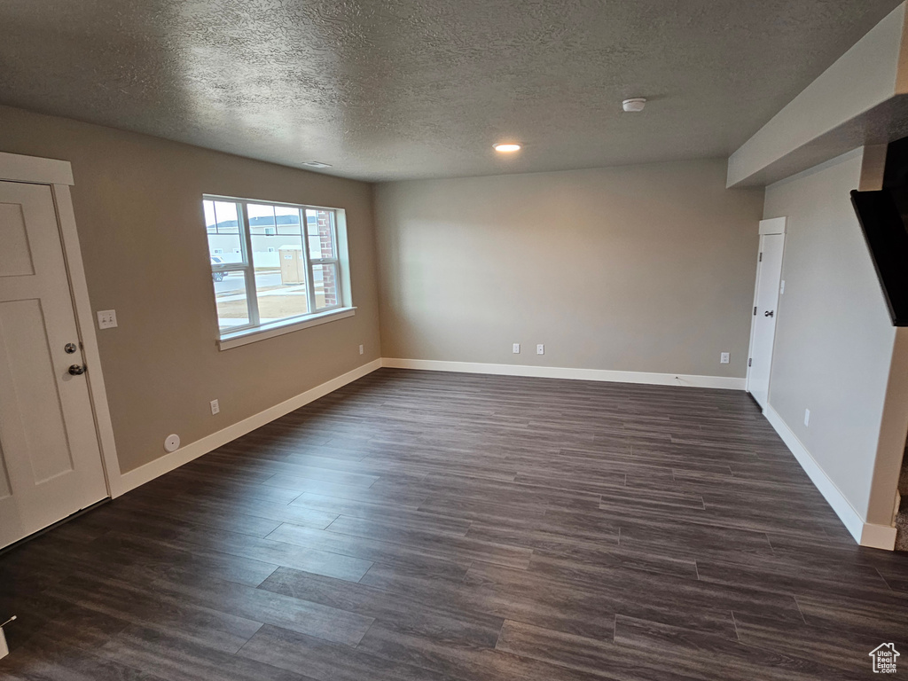 Empty room with dark wood-type flooring and a textured ceiling