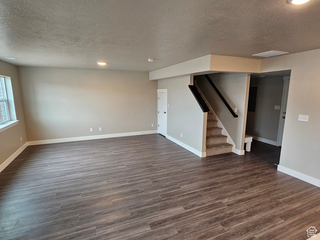 Unfurnished living room with dark hardwood / wood-style flooring and a textured ceiling