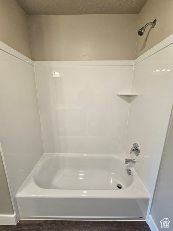 Bathroom with tub / shower combination and a textured ceiling