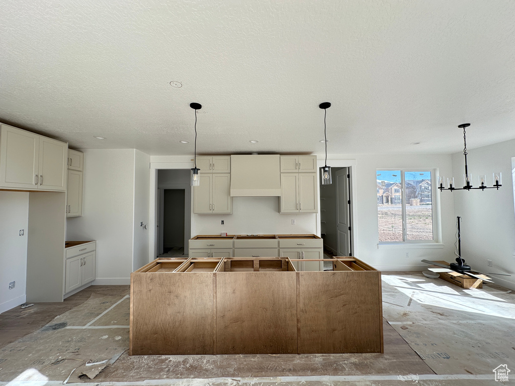 Kitchen featuring baseboards, a center island, a textured ceiling, and pendant lighting
