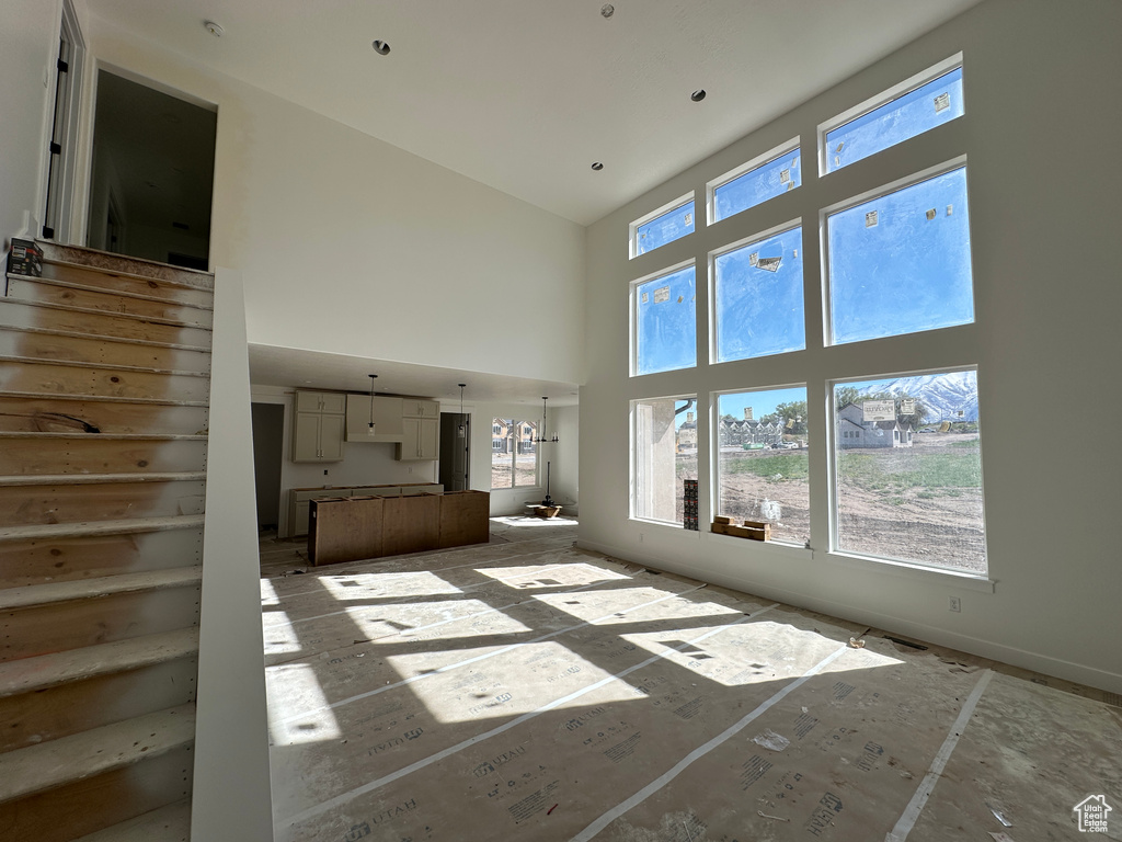 Unfurnished living room featuring a towering ceiling, a wealth of natural light, and stairway