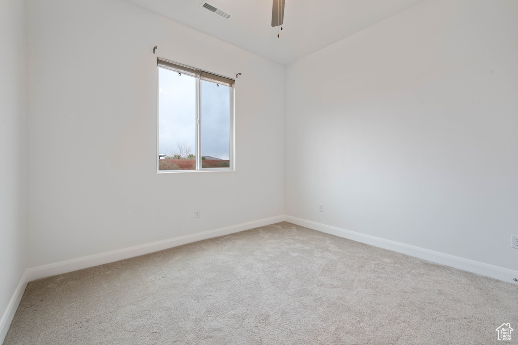 Carpeted empty room featuring ceiling fan