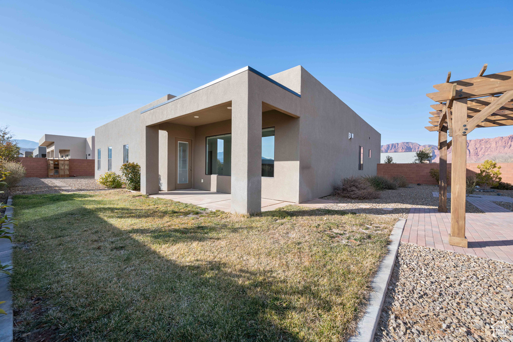 Rear view of house featuring a mountain view, a patio, a pergola, and a lawn