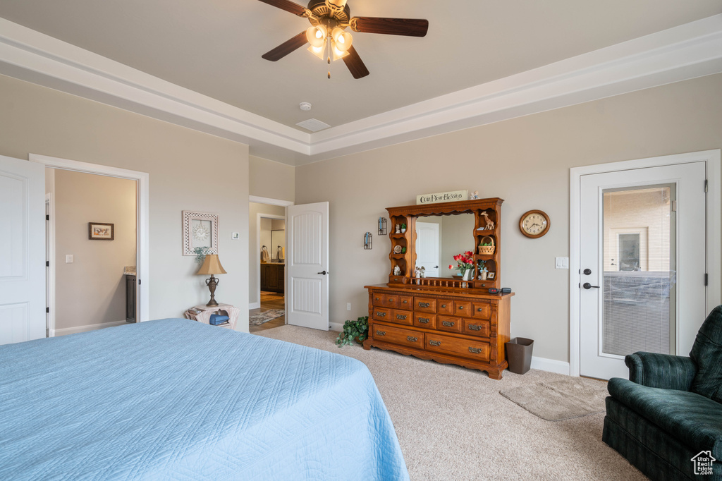 Carpeted bedroom featuring ensuite bath, ceiling fan, and a raised ceiling