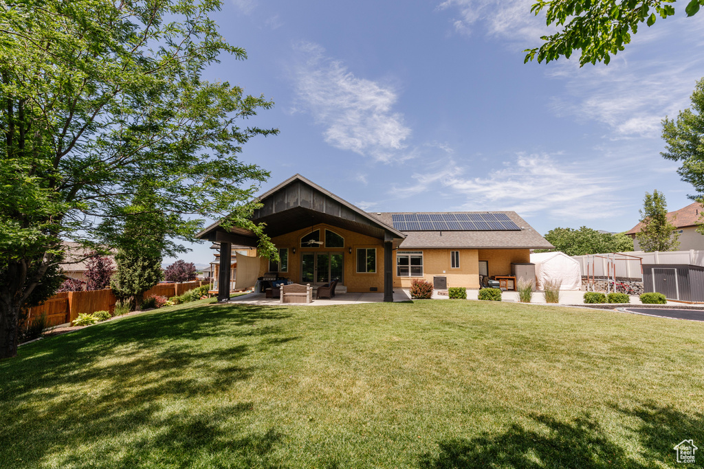 Rear view of house with roof mounted solar panels, a patio, an outdoor living space, and roof with shingles