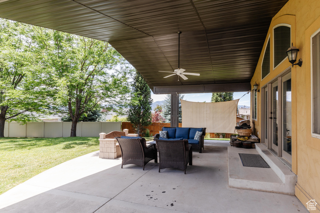 Fenced backyard with an outdoor hangout area, a patio area, and ceiling fan