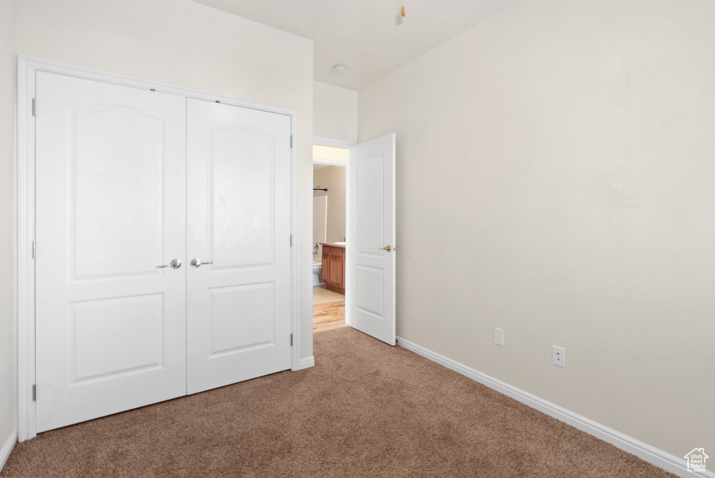 Unfurnished bedroom featuring a closet and light colored carpet