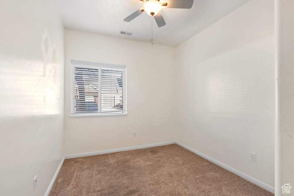 Carpeted spare room featuring ceiling fan