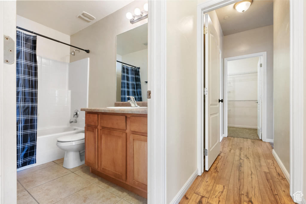 Full bathroom featuring shower / tub combo with curtain, toilet, vanity, and tile patterned floors