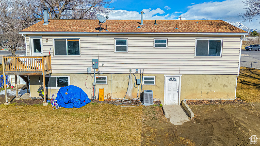 Rear view of property with a deck, a lawn, and central air condition unit