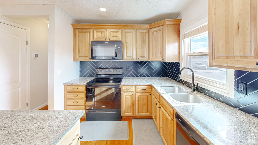 Kitchen featuring light brown cabinetry, sink, black appliances, a textured ceiling, and backsplash