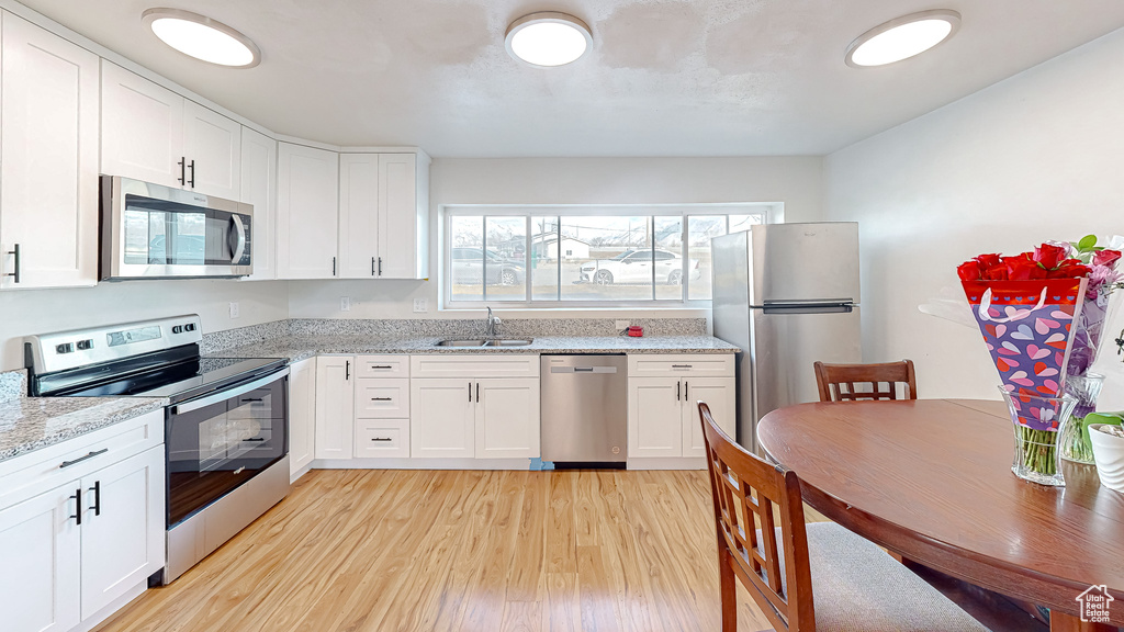 Kitchen featuring stainless steel appliances, sink, and white cabinets