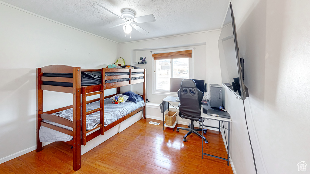 Bedroom featuring ceiling fan, a textured ceiling, and light wood-type flooring