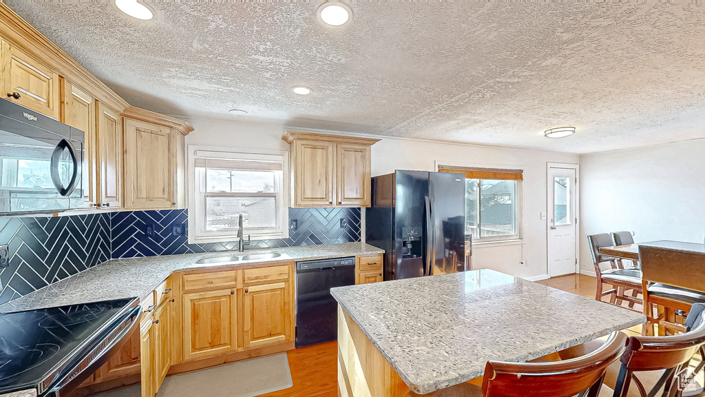 Kitchen with plenty of natural light, sink, a kitchen island, and black appliances