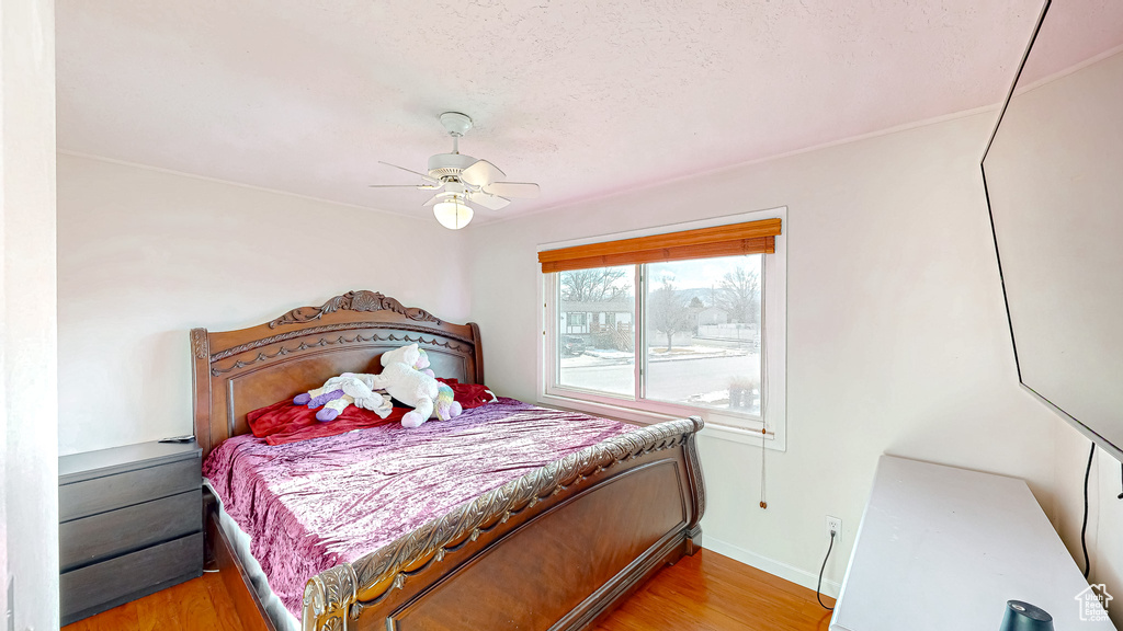 Bedroom featuring ceiling fan, light hardwood / wood-style flooring, and a textured ceiling