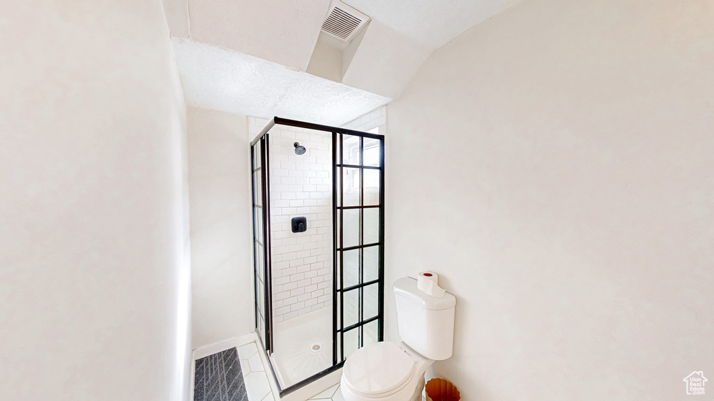 Bathroom featuring toilet, tile patterned floors, and a shower with shower door