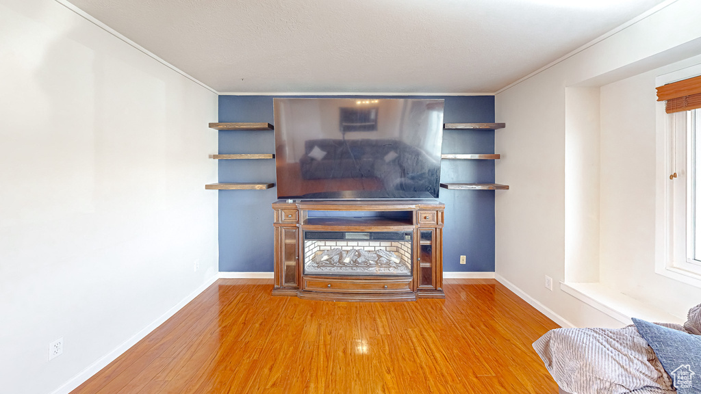 Unfurnished living room with hardwood / wood-style flooring and crown molding