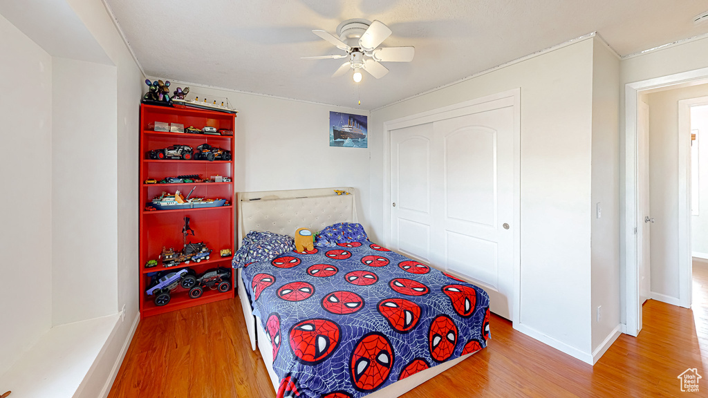 Bedroom with hardwood / wood-style flooring, ceiling fan, and a closet