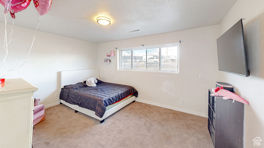 Bedroom featuring light carpet and a textured ceiling