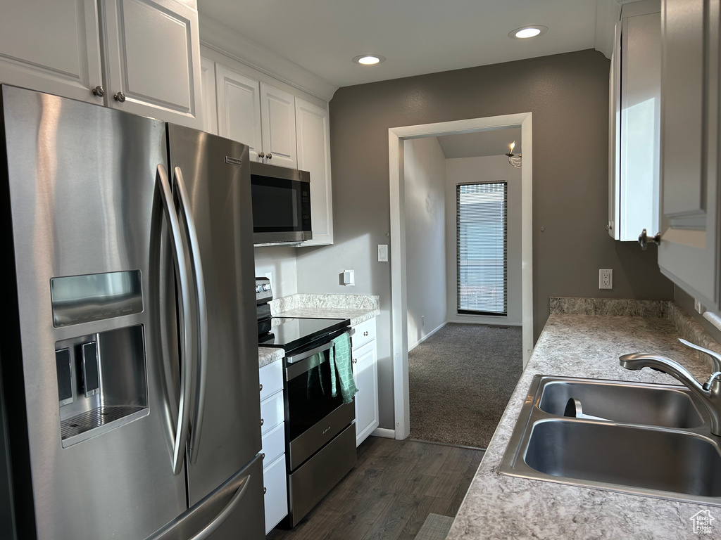 Kitchen with dark wood-type flooring, sink, stainless steel appliances, and white cabinets