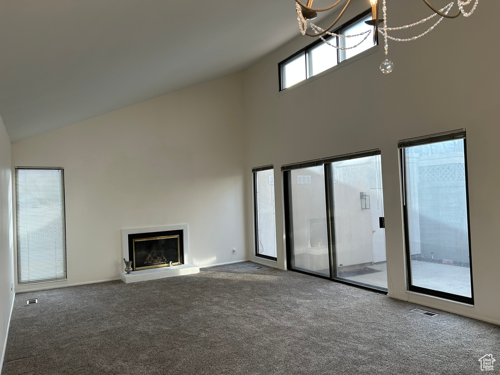 Unfurnished living room featuring carpet and high vaulted ceiling