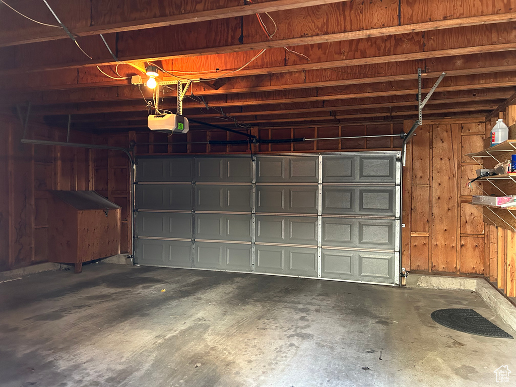 Garage featuring a garage door opener and wood walls