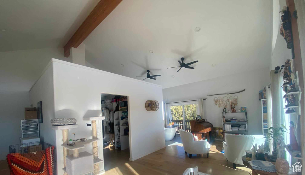 Interior space with ceiling fan, high vaulted ceiling, beamed ceiling, and wood finished floors